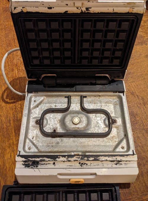 Intérieur du gaufrier avec une plaque à gaufre démontée, laissant la résistance visible