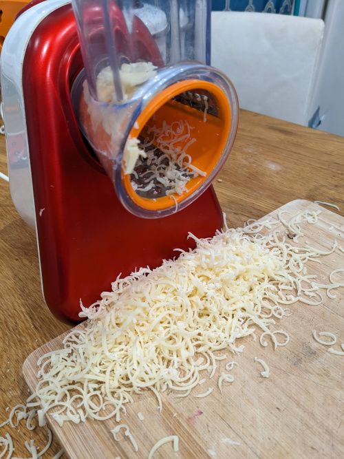 Emmental râpé finement à la sortie de l’appareil, sur une planche à découper en bois