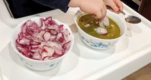 Un bol de radis coupés finement à côté d’un bol de soupe, avec quelques rondelles de radis en topping