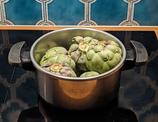 Cinq artichauts dans une cocotte-minute posée sur une plaque à induction