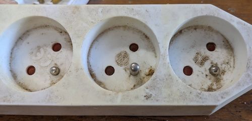 Vue rapprochée montrant les deux broches de terre enfoncées dans le boîtier de la multiprise