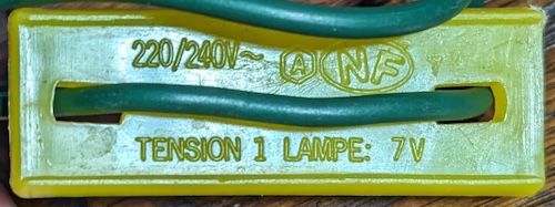 Face de la plaque jaune indiquant « 220/240V~ NF TENSION 1 LAMPE: 7V »