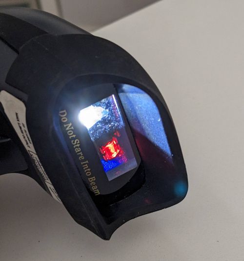Vue rapprochée de la tête du scanner avec la LED d’éclairage et le laser allumés.