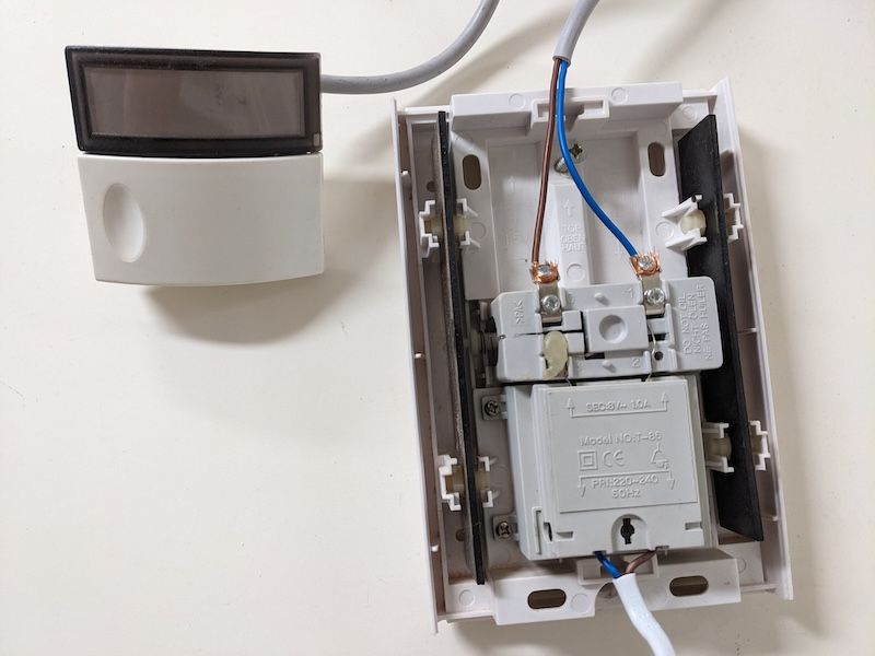 Photo montrant le carillon ouvert, avec un bouton poussoir et un câble d’alimentation raccordés.